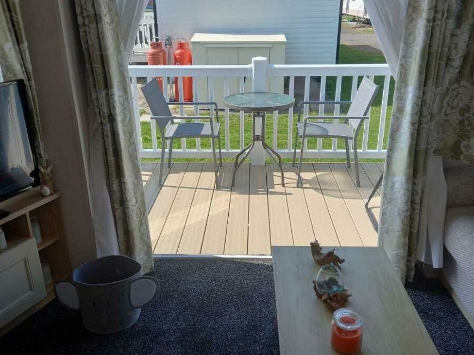 a deck with a table and chairs visible through an open doorway at Skegness Holiday Park - Holiday Accommodation 13968, Skegness