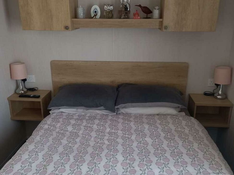 a bedroom featuring a bed with pillows and a blanket, bedside tables with lamps and decor at Skegness Holiday Park - Holiday Accommodation 13968 in Skegness