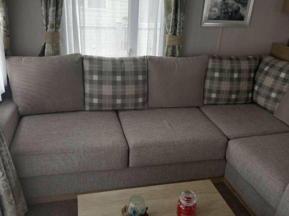 a corner sofa with checkered cushions and a wooden table at Skegness Holiday Park - Holiday Accommodation 13968, Skegness