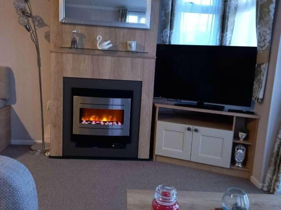 a living room with a fireplace and television at Skegness Holiday Park - Holiday Accommodation 13968 in Skegness