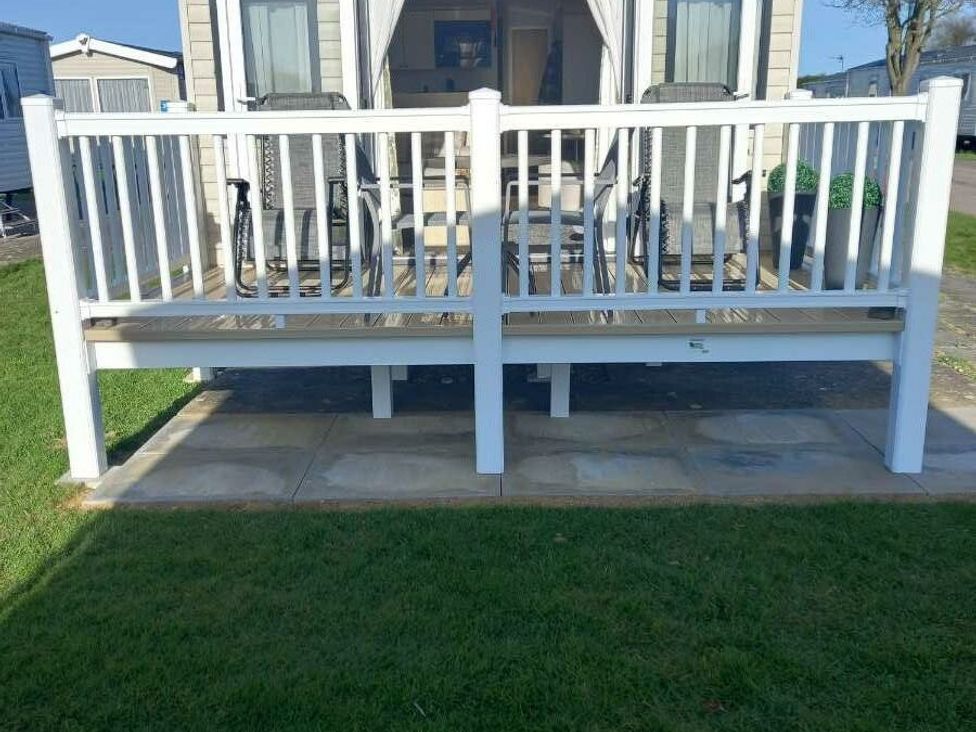 a wooden deck with railings and two chairs at Skegness Holiday Park - Holiday Accommodation 13968 in Skegness