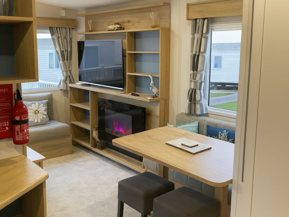 A living room with a television, sofa, and dining table at Reighton Sands Holiday Park - Holiday Accommodation 14875, Filey