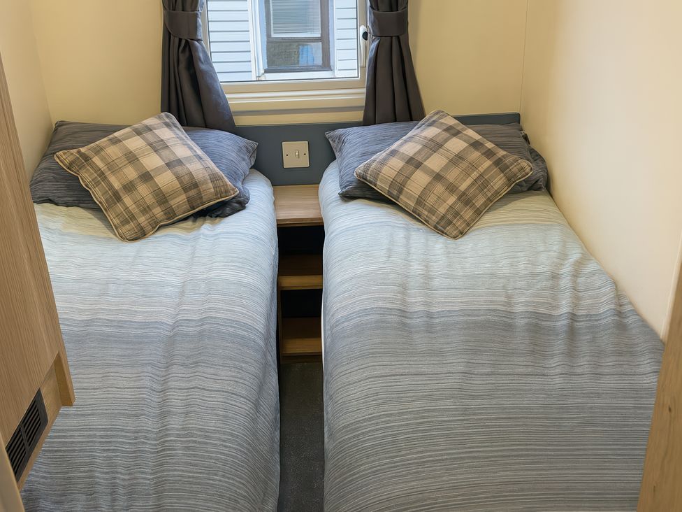 A bedroom with two single beds and a window at Reighton Sands Holiday Park - Holiday Accommodation 14875, Filey