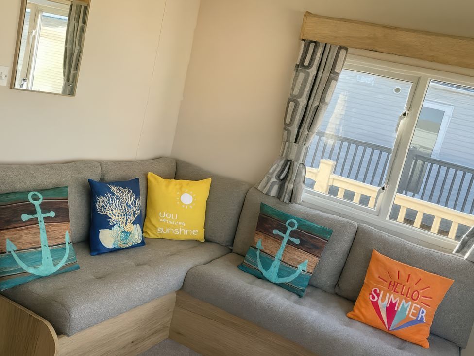 A living room with a couch and decorative pillows at Reighton Sands Holiday Park - Holiday Accommodation 14875, Filey