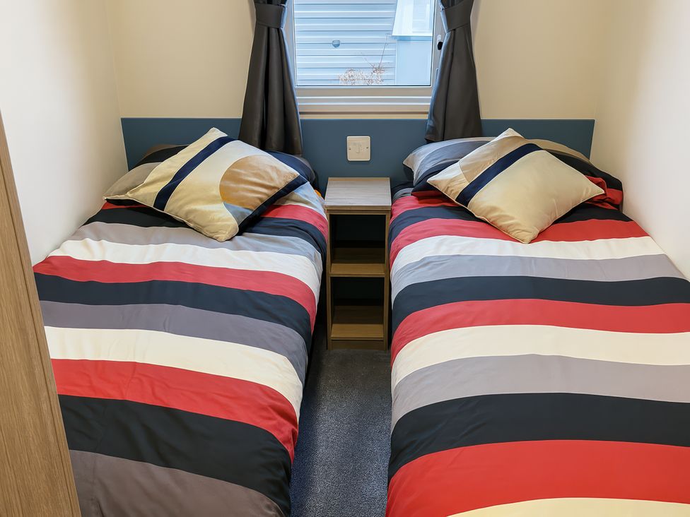 A bedroom with two beds and a nightstand at Reighton Sands Holiday Park - Holiday Accommodation 14875, Filey