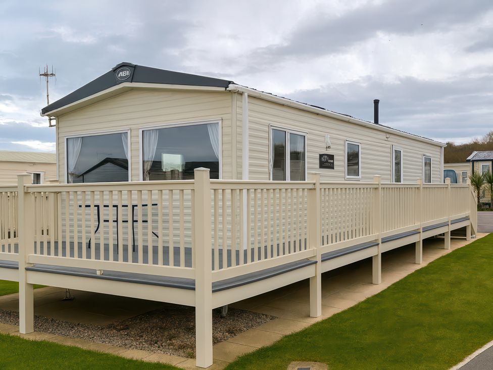 A mobile home with a deck and table at Reighton Sands Holiday Park - Holiday Accommodation 14875 Filey