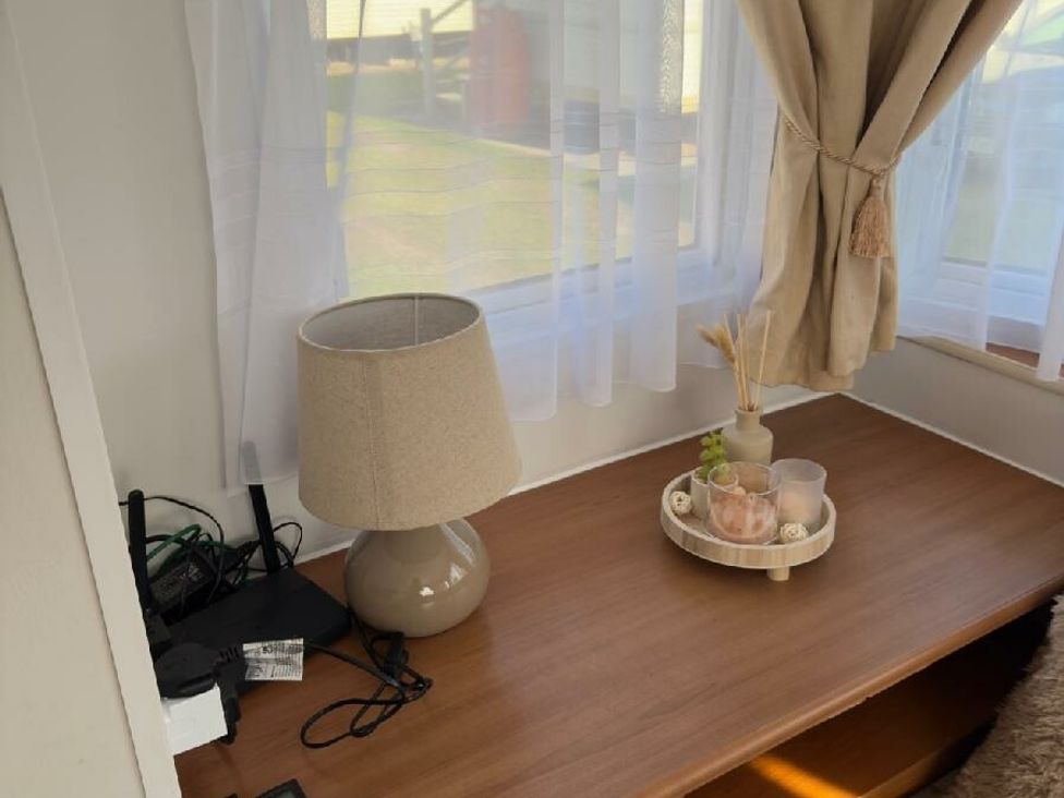 a table with a lamp and decorative items near a window at Sealands Caravan Park - Holiday Accommodation 15223 in Ingoldmells