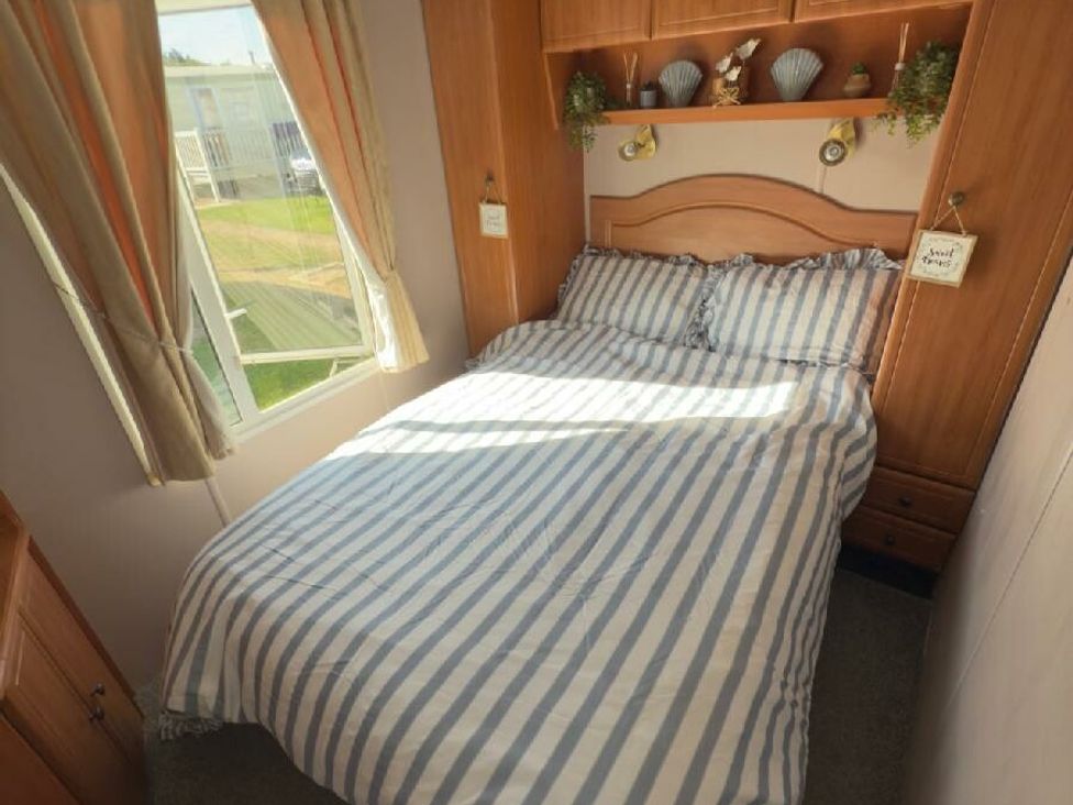 a bedroom with a bed and shelves at Sealands Caravan Park - Holiday Accommodation 15223 in Ingoldmells