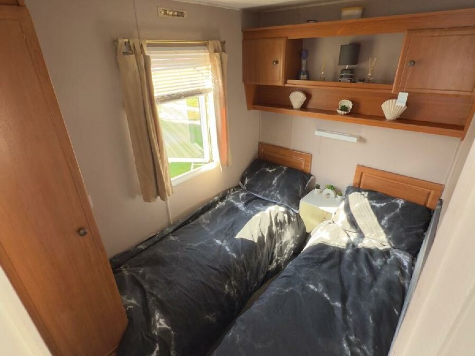 a bedroom with two single beds and a shelf above at Sealands Caravan Park - Holiday Accommodation 15223 in Ingoldmells