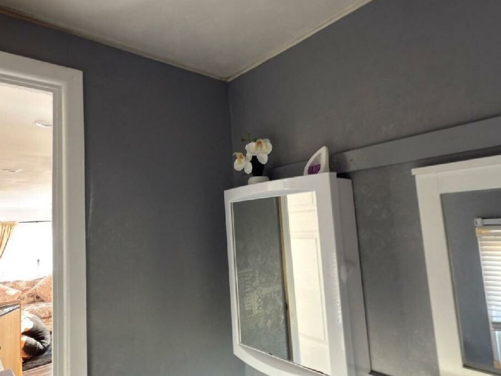 a bathroom with a mirror cabinet and a small flower decoration at Sealands Caravan Park - Holiday Accommodation 15223 in Ingoldmells