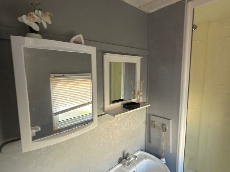 a bathroom with mirrors and a shower at Sealands Caravan Park - Holiday Accommodation 15223 in Ingoldmells