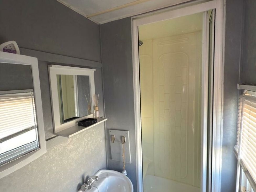a bathroom with a shower stall, sink, and mirror at Sealands Caravan Park - Holiday Accommodation 15223 In Ingoldmells