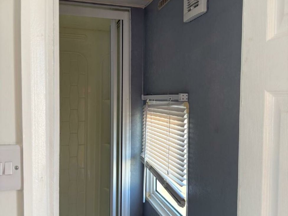 a small bathroom area with a shower and a window with blinds at Sealands Caravan Park - Holiday Accommodation 15223 in Ingoldmells