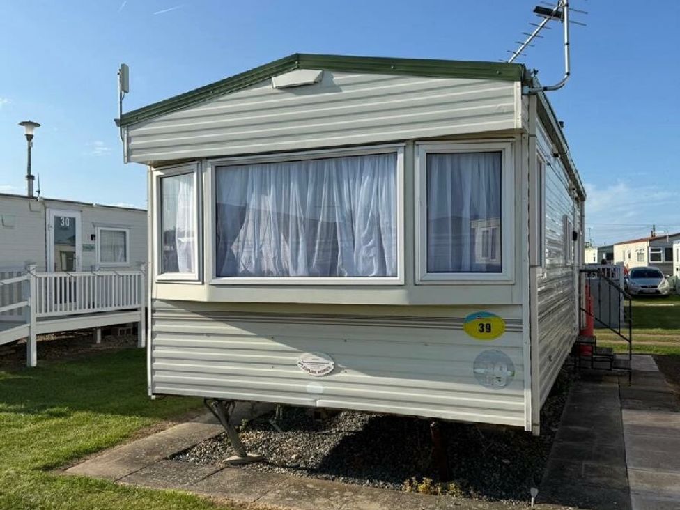 a caravan with a large window and curtains at Sealands Caravan Park - Holiday Accommodation 15223 in Ingoldmells