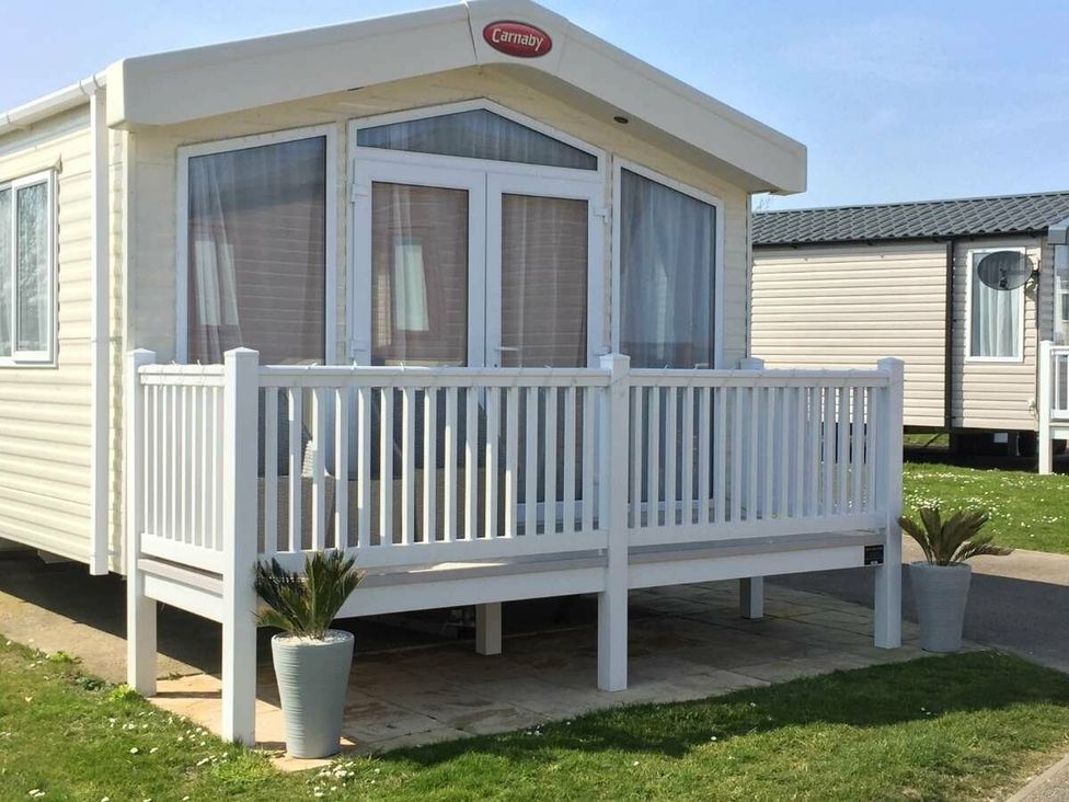 a holiday home with a deck and potted plants at Hopton Holiday Village - Holiday Accommodation 15473, Great Yarmouth