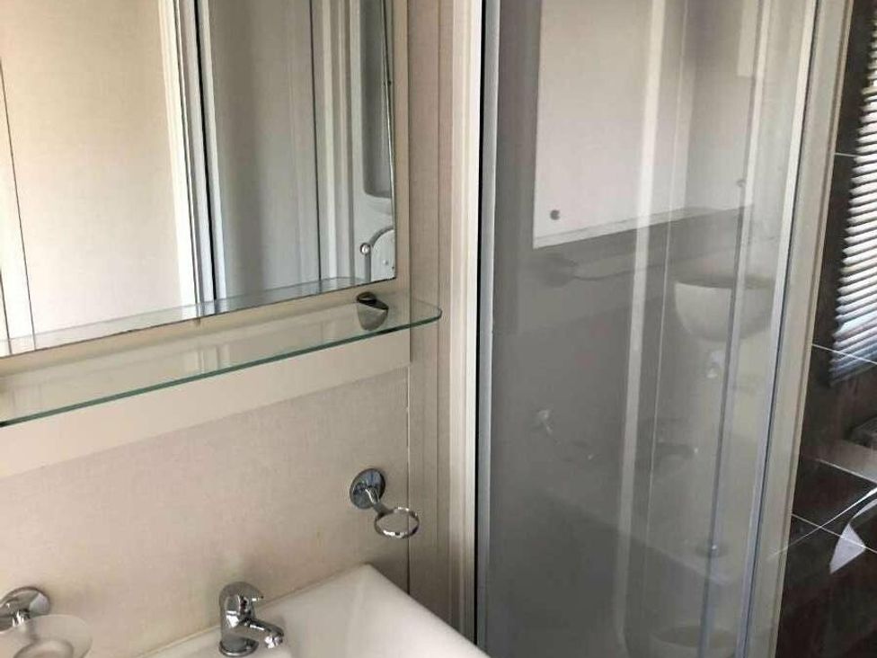 a bathroom with a sink, mirror, and shower enclosure at Hopton Holiday Village - Holiday Accommodation 15473, Great Yarmouth