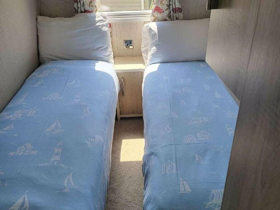 a bedroom with two single beds and a nightstand at Hopton Holiday Village - Holiday Accommodation 15473, Great Yarmouth