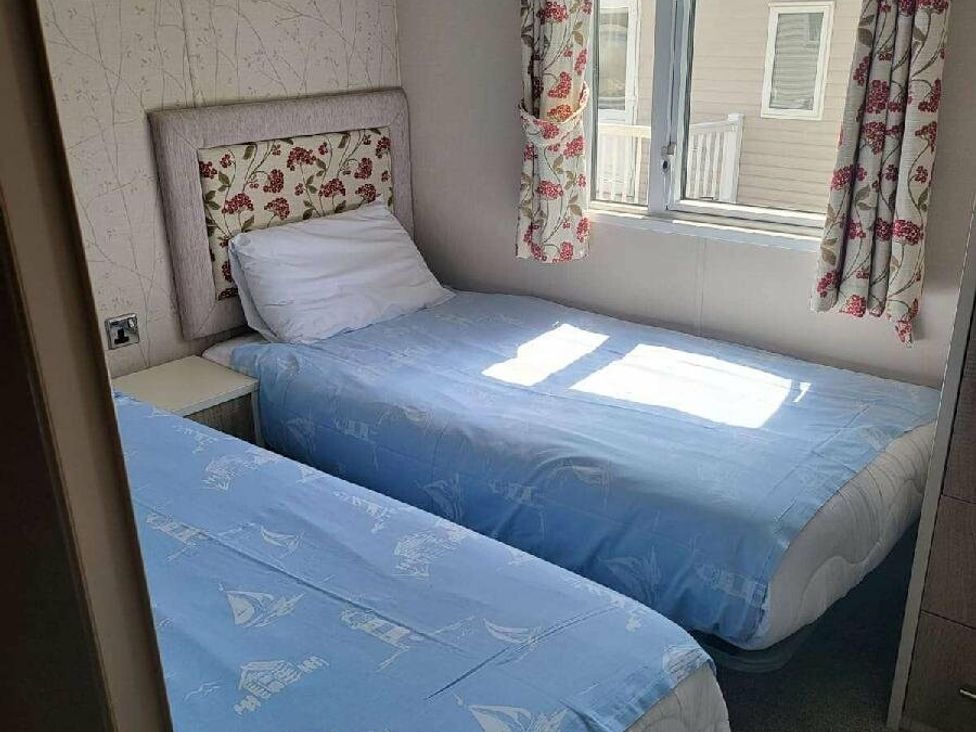 a bedroom with two single beds and floral curtains at Hopton Holiday Village - Holiday Accommodation 15473 in Great Yarmouth