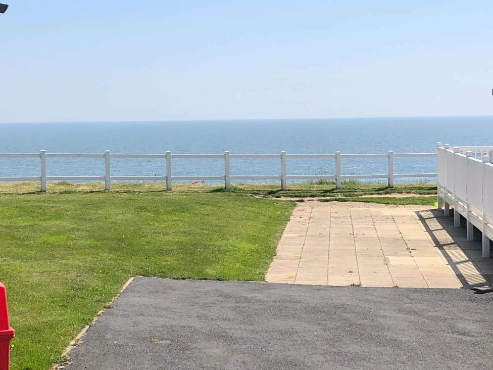 a view of the sea from a grassy area with a pathway at Hopton Holiday Village - Holiday Accommodation 15473, Great Yarmouth