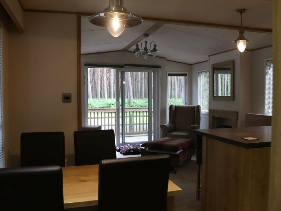 a dining area with a table and chairs next to a living room with a large window at Kelling Heath Holiday Park - Holiday Accommodation 15488 Weybourne