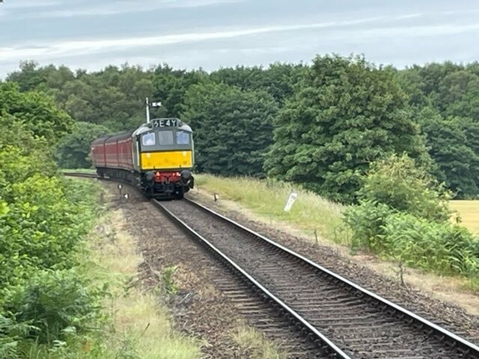 a train approaching a curve on railway tracks surrounded by trees at Kelling Heath Holiday Park - Holiday Accommodation 15488 Weybourne