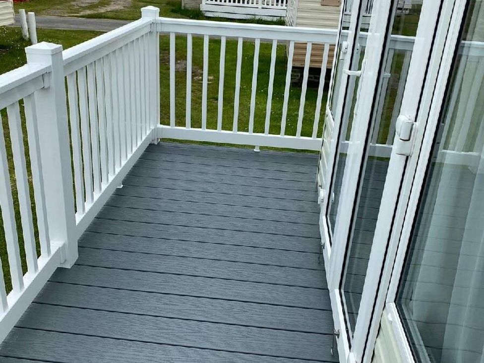 a deck with gray flooring and white railing at Lyons Sunnysands Holiday Park - Holiday Accommodation 15526 in Barmouth