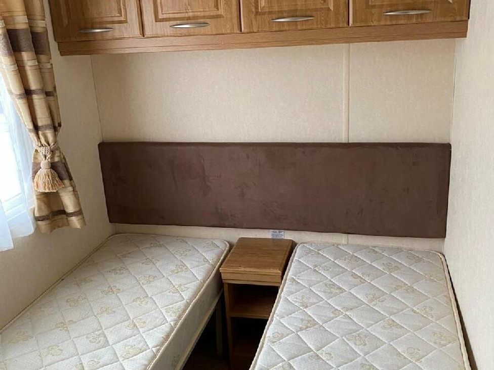 a bedroom with two single beds and a nightstand at Lyons Sunnysands Holiday Park - Holiday Accommodation 15526, Barmouth