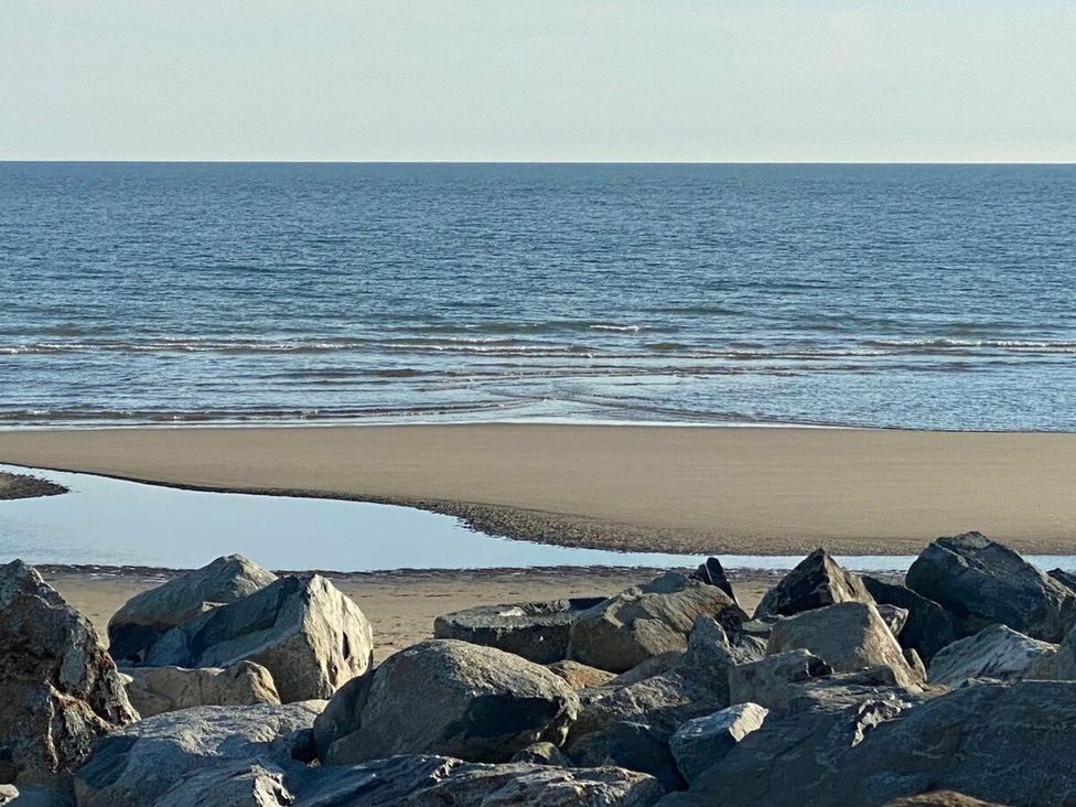 a rocky shore with a view of the ocean and sand at Lyons Sunnysands Holiday Park - Holiday Accommodation 15526, Barmouth