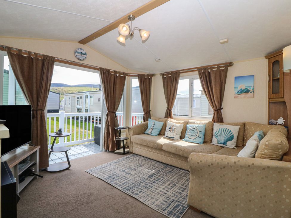 A living room with a sofa and television at Sunnysands in Talybont near Barmouth