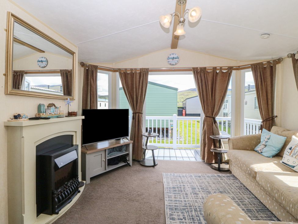 A living room with a fireplace and television at Sunnysands in Talybont near Barmouth