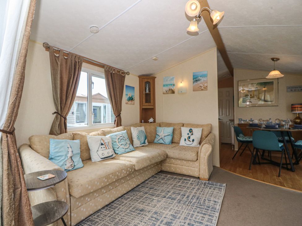 A living room with a sofa and dining area at Sunnysands in Talybont near Barmouth
