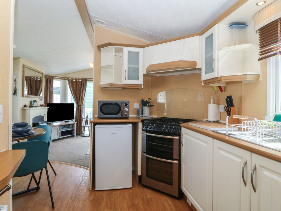 A kitchen with an oven and refrigerator at Sunnysands in Talybont near Barmouth