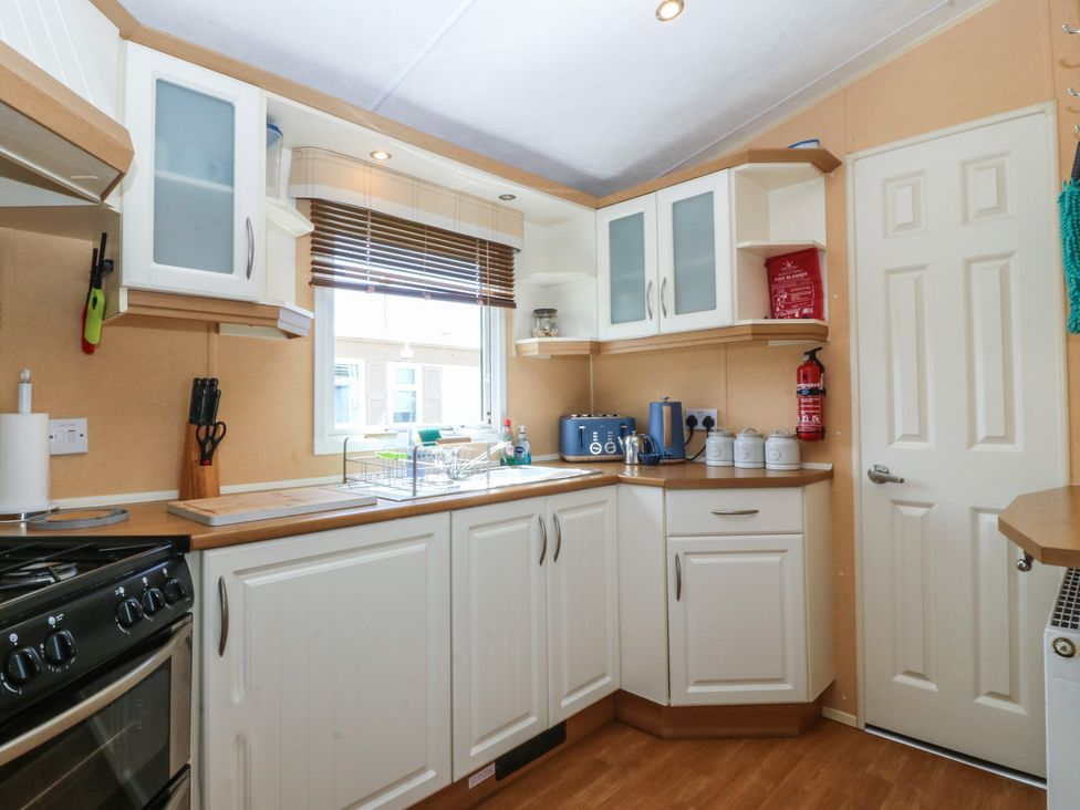 A kitchen with cabinets and appliances at Sunnysands in Talybont near Barmouth