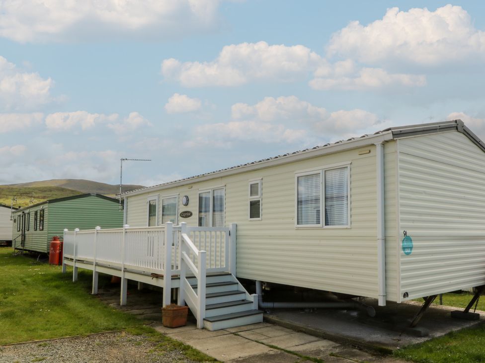 A mobile home with a deck and stairs at Sunnysands in Talybont near Barmouth