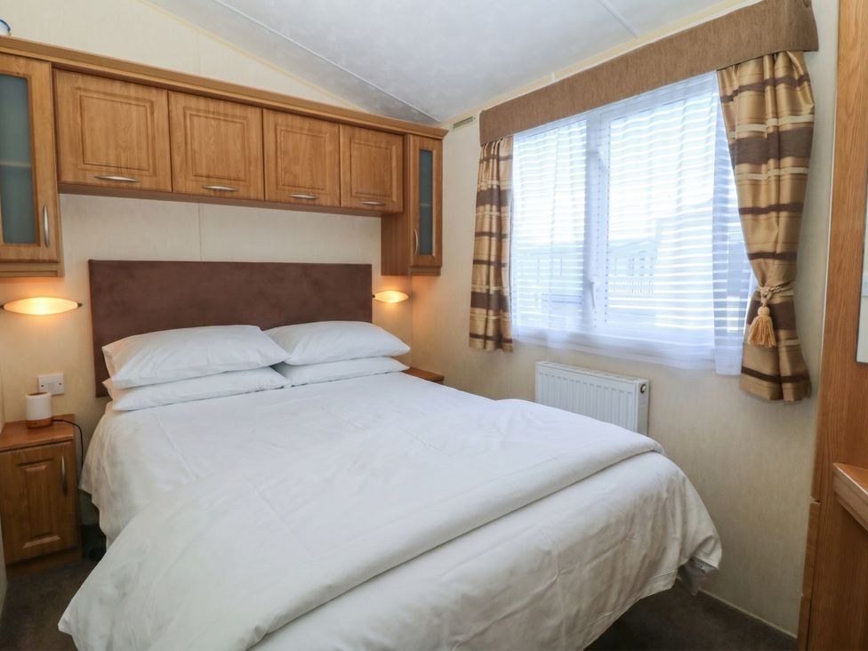 A bedroom with a bed and wall-mounted cabinets at Sunnysands in Talybont near Barmouth