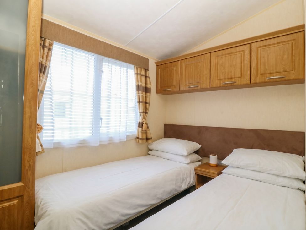 A bedroom with two beds and a window at Sunnysands in Talybont near Barmouth