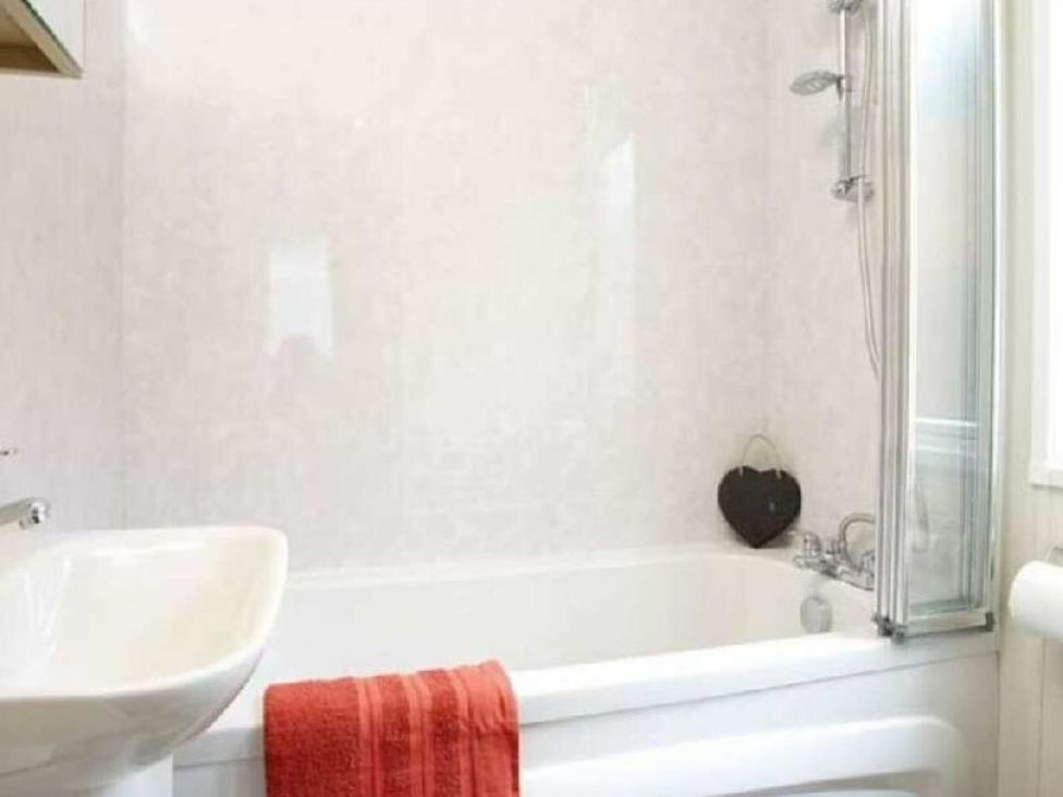 a bathroom with a bathtub, sink, and a red towel at Shorefield Country Park - Holiday Accommodation 15558, Milford On Sea