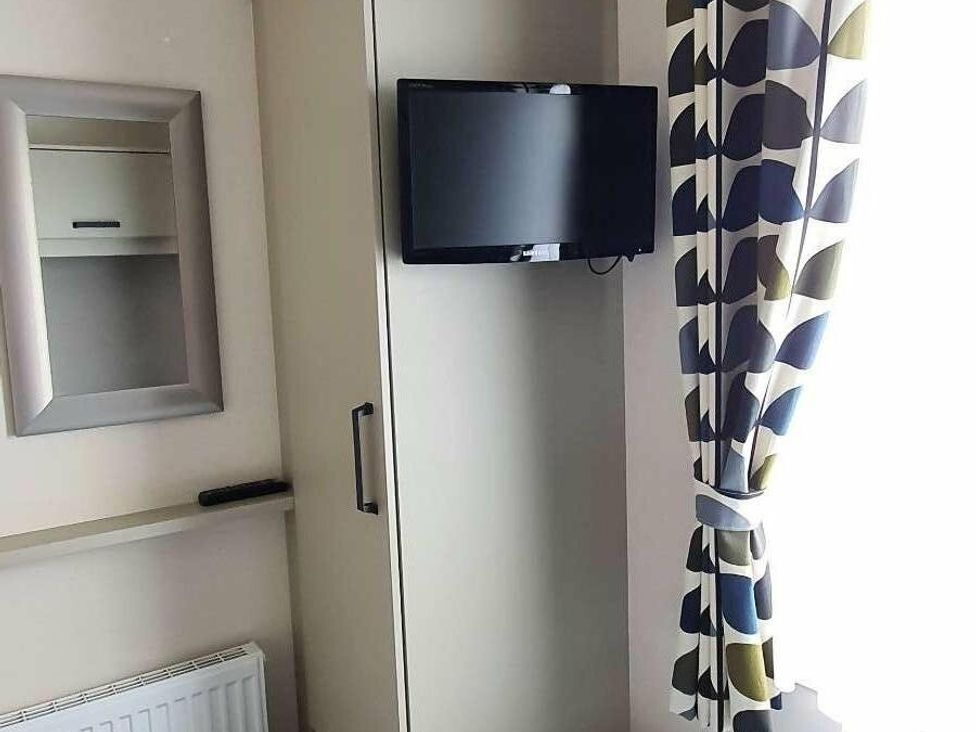 a wall with a mirror and a TV mounted above a wardrobe at Shorefield Country Park - Holiday Accommodation 15558, Milford On Sea