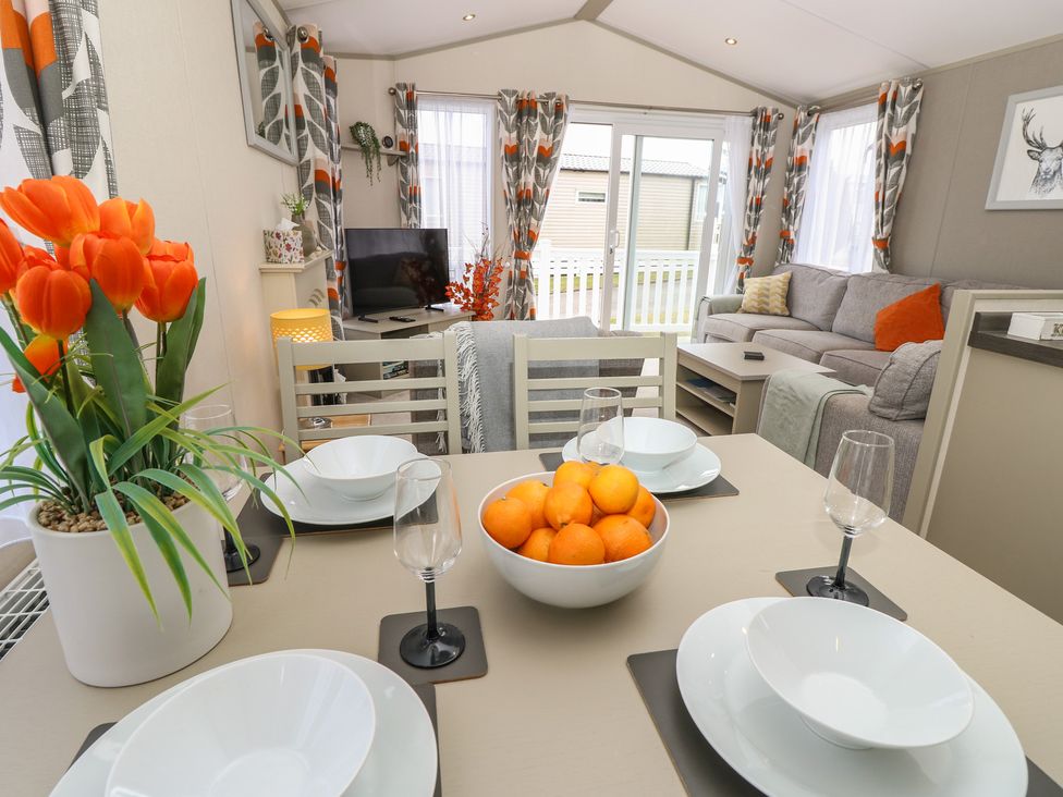 A dining area with a table set and a sofa in the background at Pine Tree Lodge - Shorefield Country Park Milford On Sea