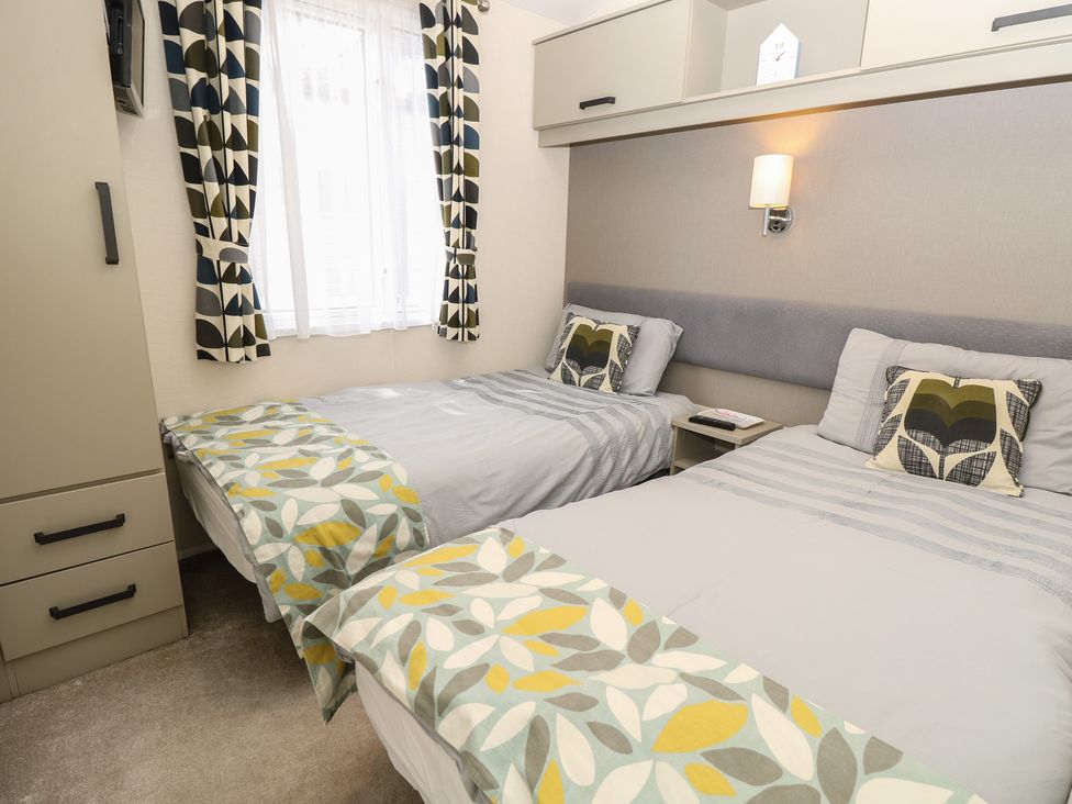 A bedroom with two beds and a bedside table at Pine Tree Lodge - Shorefield Country Park Milford On Sea