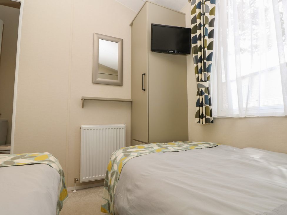 A bedroom with two beds and a television at Pine Tree Lodge - Shorefield Country Park, Milford On Sea
