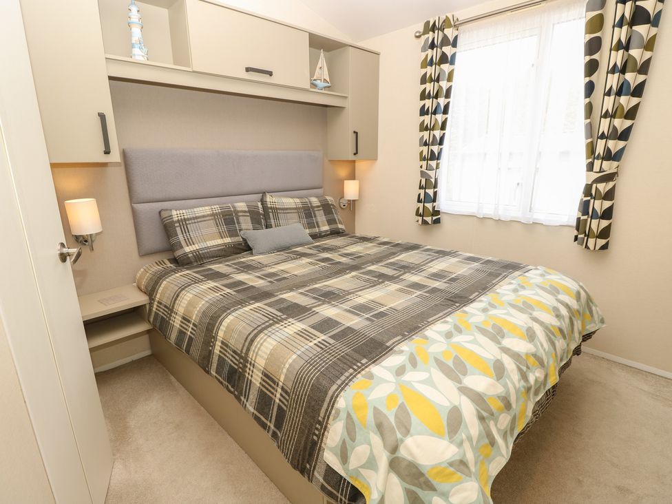 A bedroom with a double bed and nightstand at Pine Tree Lodge - Shorefield Country Park Milford On Sea