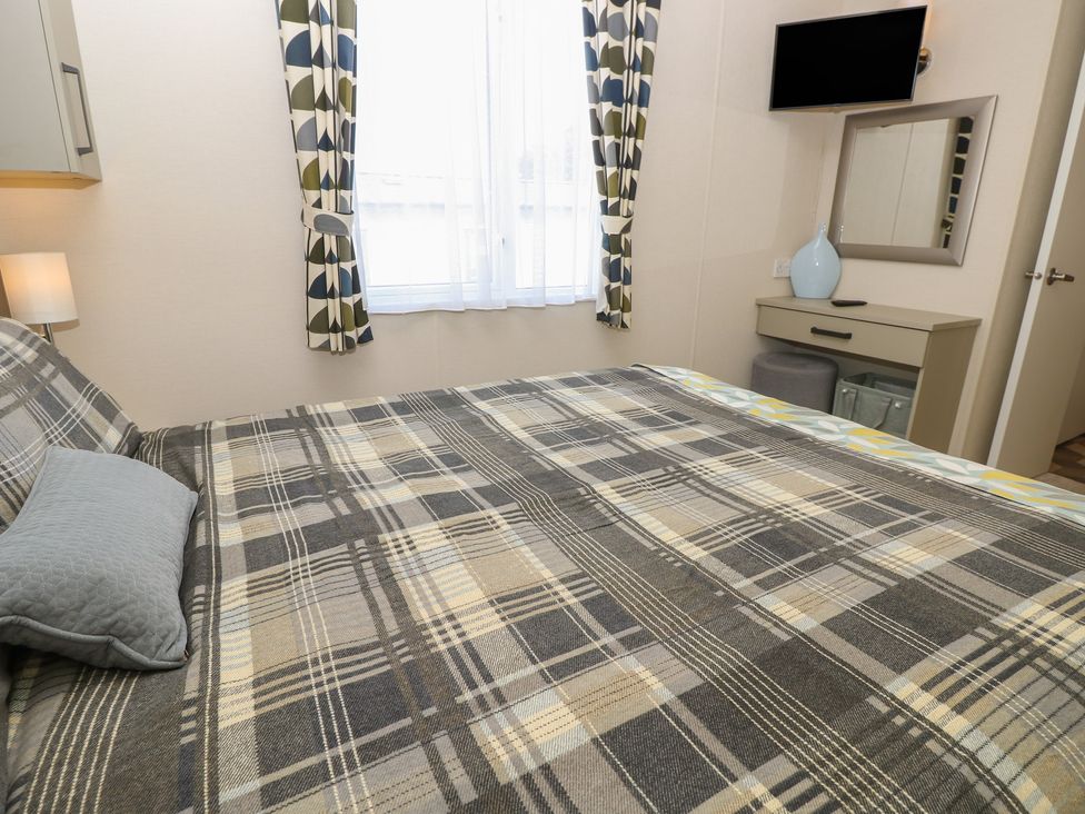 A bedroom with a bed and nightstand at Pine Tree Lodge - Shorefield Country Park, Milford On Sea