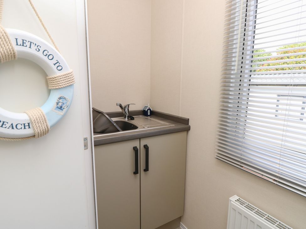 A utility room with a sink and a lifebuoy at Pine Tree Lodge - Shorefield Country Park, Milford On Sea