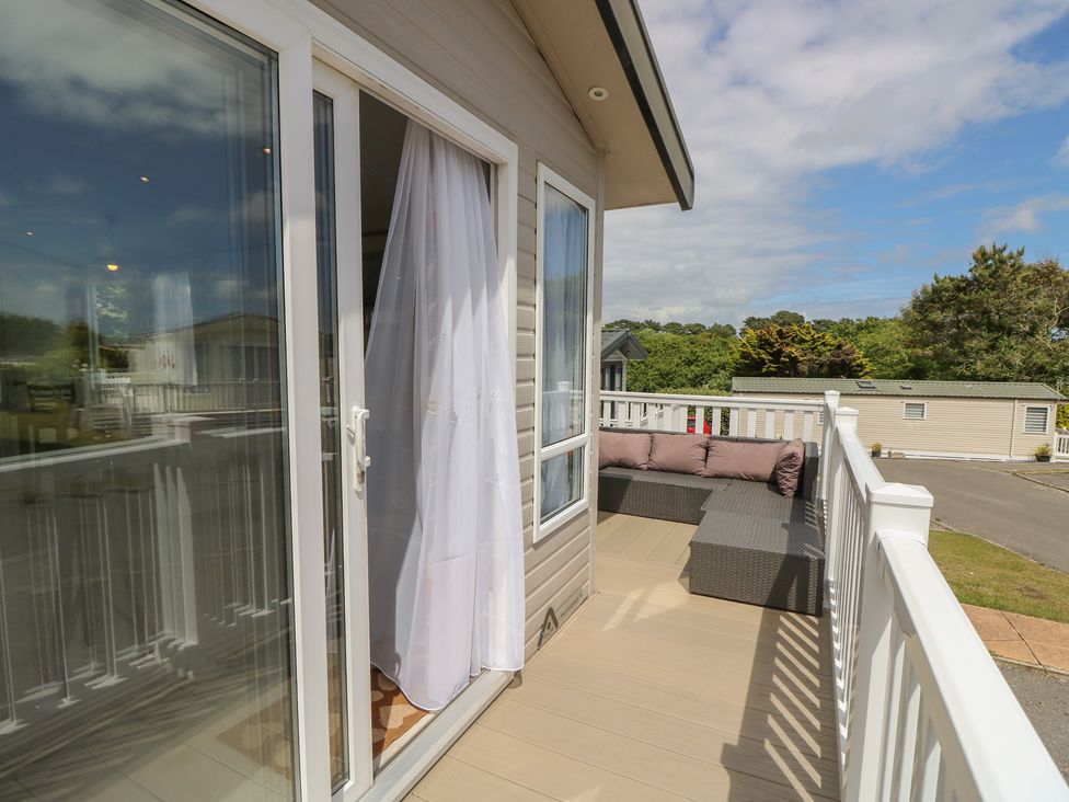 A balcony with a sofa and curtain at Pine Tree Lodge - Shorefield Country Park, Milford On Sea