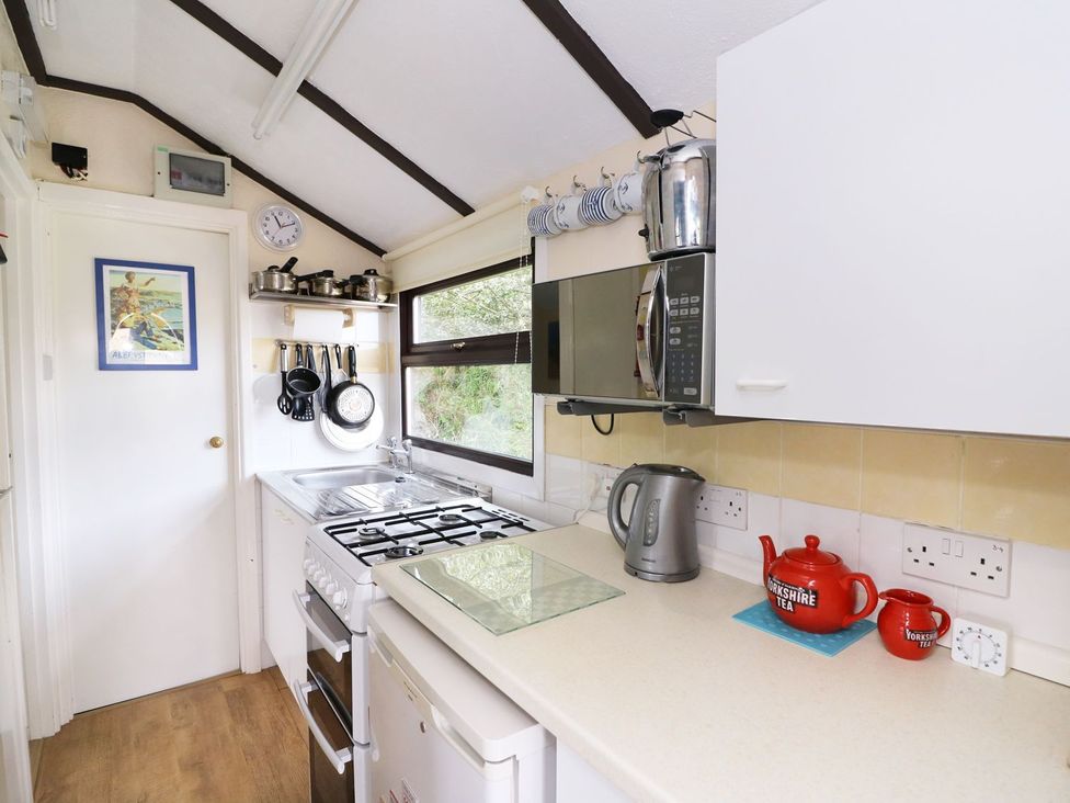 A kitchen with a gas stove and kettle at Captain's Cabin in Clarach Bay near Aberystwyth
