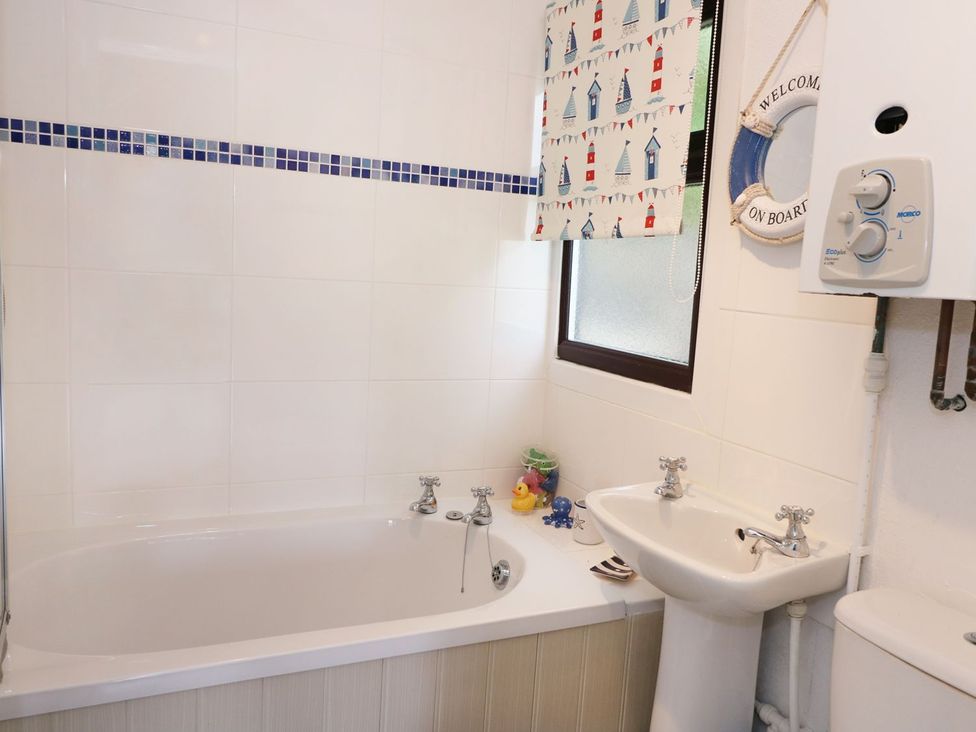 A bathroom with a bathtub and sink at Captain's Cabin in Clarach Bay near Aberystwyth