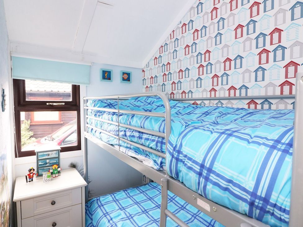 A bedroom with a bunk bed and nightstand at Captain's Cabin, Clarach Bay near Aberystwyth