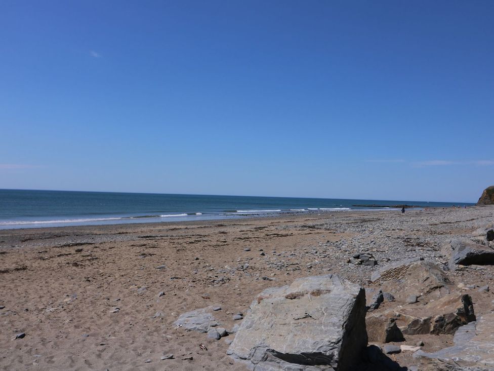 A beach with rocks and ocean waves at Captain's Cabin in Clarach Bay near Aberystwyth