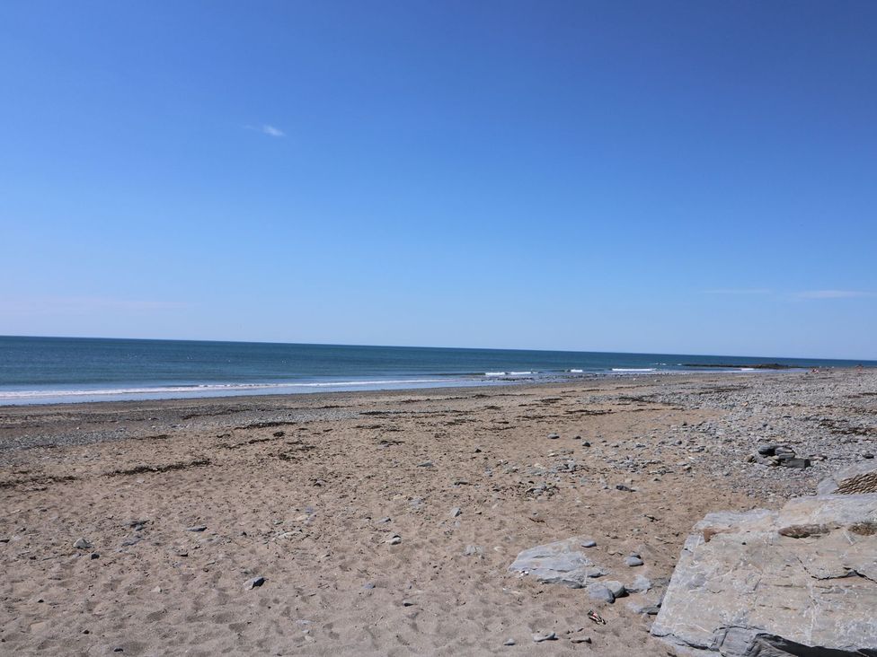 A beach with sand and water at Captain's Cabin in Clarach Bay near Aberystwyth